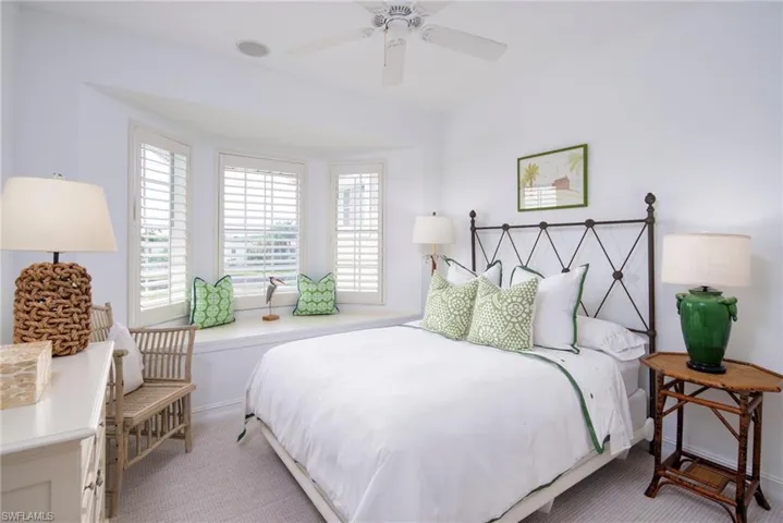 Bedroom featuring light colored carpet, baseboards, and a ceiling fan