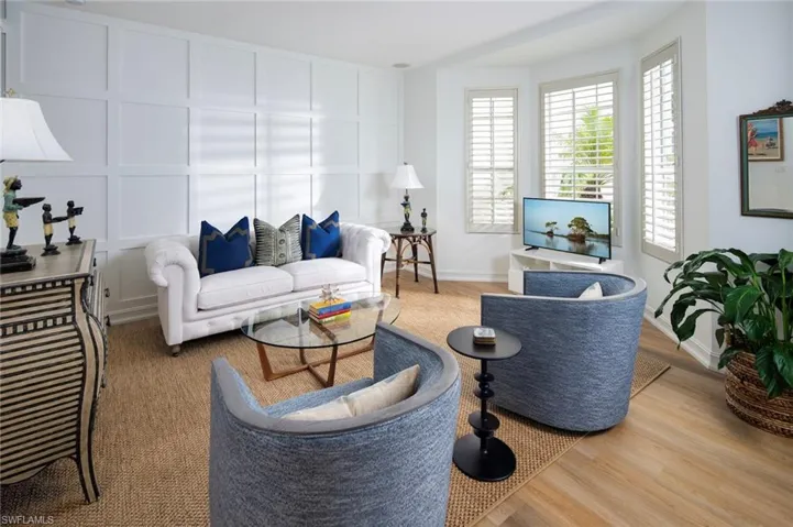 Living area with plenty of natural light, a decorative wall, wood finished floors, and baseboards
