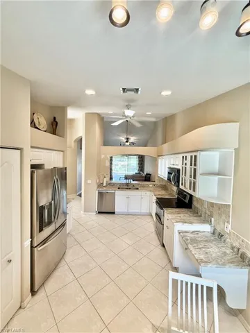 Kitchen featuring white cabinetry, stainless steel appliances, glass insert cabinets, a ceiling fan, and light tile patterned floors