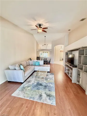 Living area featuring ceiling fan, light wood finished floors, lofted ceiling, and arched walkways