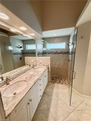 Full bath featuring double vanity, a shower stall, and healthy amount of natural light