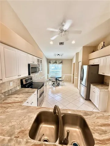 Kitchen with stainless steel appliances, tasteful backsplash, ceiling fan, light countertops, and white cabinetry