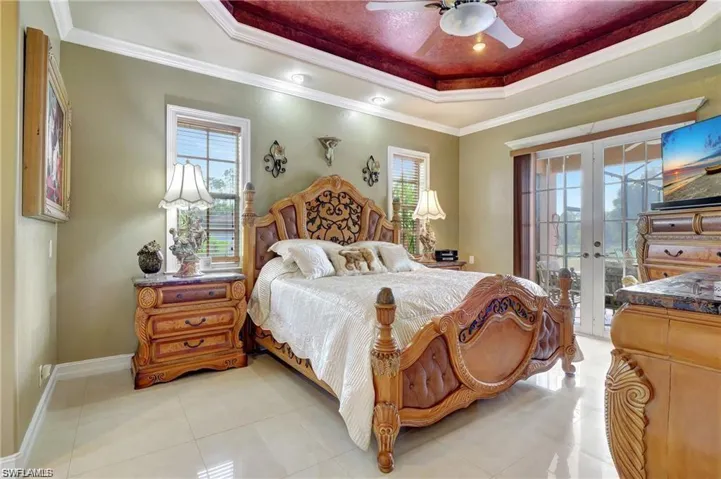 Bedroom with ornamental molding, french doors, a tray ceiling, and access to exterior