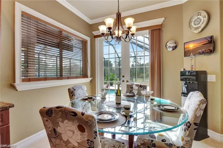 Dining space featuring french doors, crown molding, a notable chandelier, and baseboards