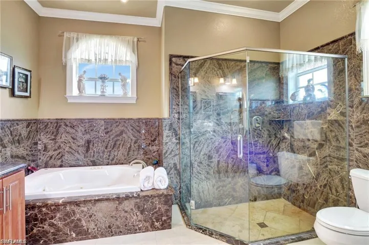 Full bath featuring toilet, a bath, a marble finish shower, and a healthy amount of sunlight