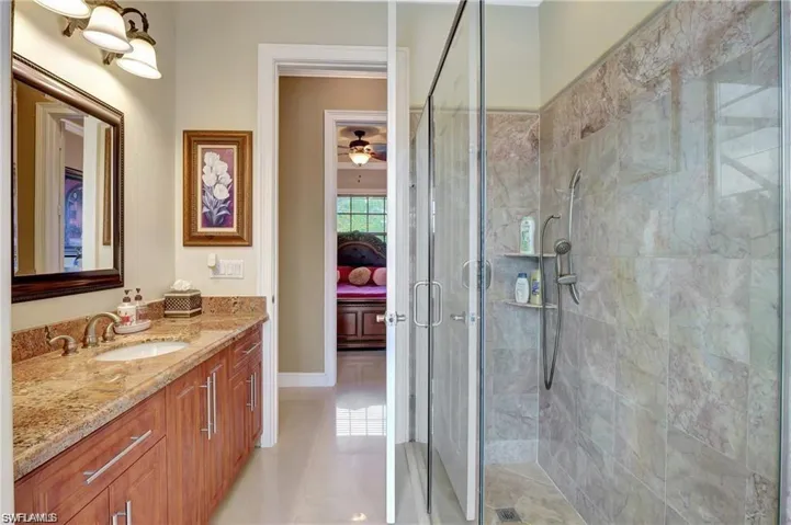 Bathroom featuring vanity, connected bathroom, a ceiling fan, and a stall shower