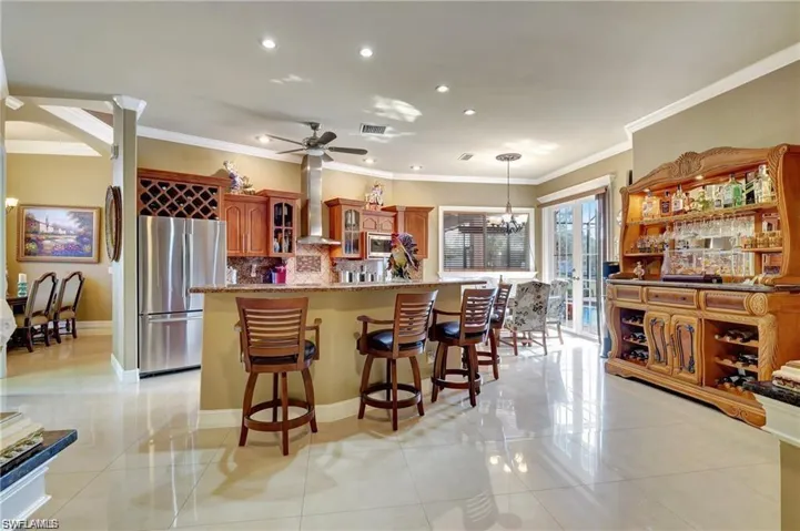 Kitchen featuring decorative backsplash, appliances with stainless steel finishes, ornamental molding, wall chimney exhaust hood, and light tile patterned flooring