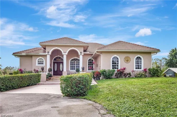 Mediterranean / spanish home with stucco siding, a front yard, and a tiled roof