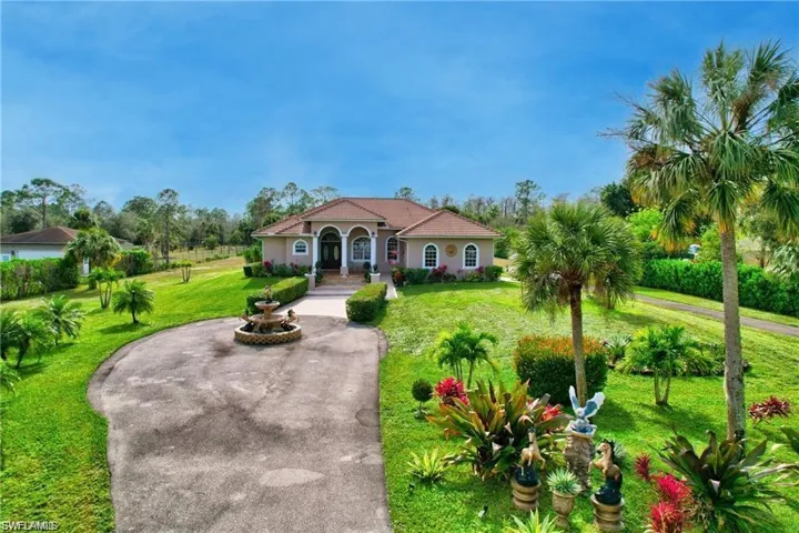 Mediterranean / spanish-style home featuring stucco siding, a front yard, and curved driveway