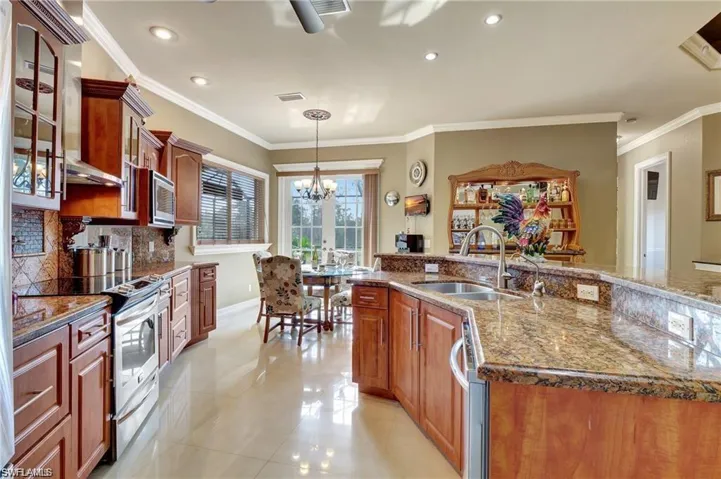 Kitchen with a sink, a chandelier, stainless steel appliances, light tile patterned flooring, and visible vents