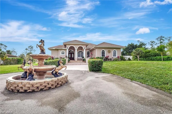 Mediterranean / spanish home featuring stucco siding, a front lawn, and curved driveway