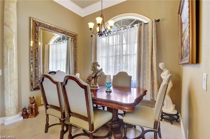 Dining space featuring crown molding, tile patterned flooring, an inviting chandelier, and baseboards