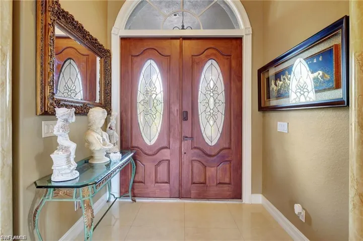 Foyer with light tile patterned flooring and baseboards