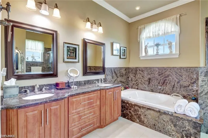 Full bath featuring tile patterned floors, ornamental molding, a garden tub, and a sink