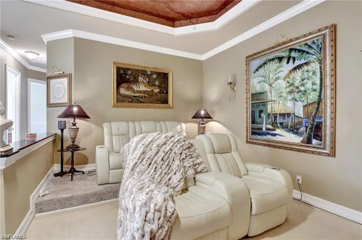 Sitting room featuring light tile patterned floors, a raised ceiling, ornamental molding, and baseboards