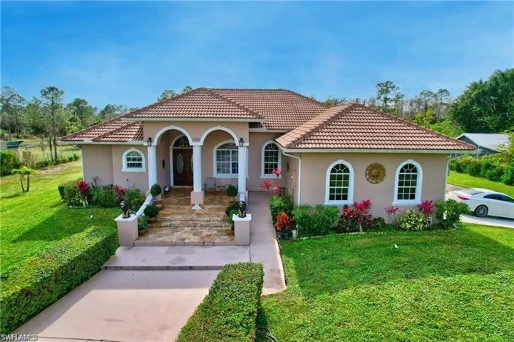 Mediterranean / spanish-style home featuring covered porch, stucco siding, a front yard, and a tiled roof