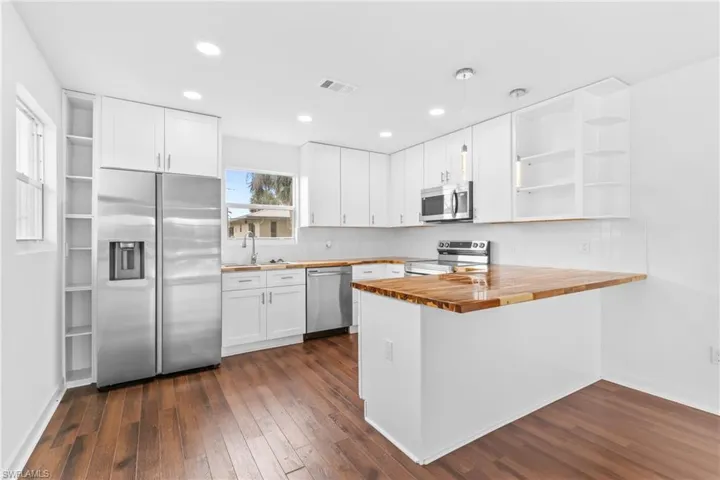 Kitchen featuring open shelves, butcher block counters, white cabinetry, and recessed lighting