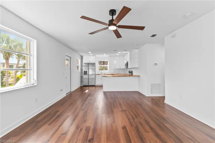 Unfurnished living room featuring dark wood-type flooring and ceiling fan