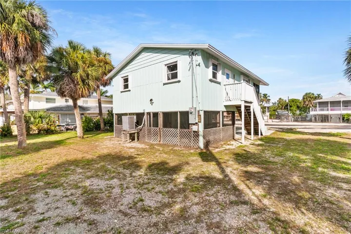 Rear view of property featuring a sunroom, stairway, and a yard