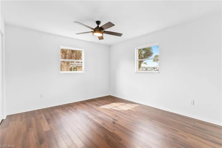 Empty room featuring dark wood-style flooring and a ceiling fan