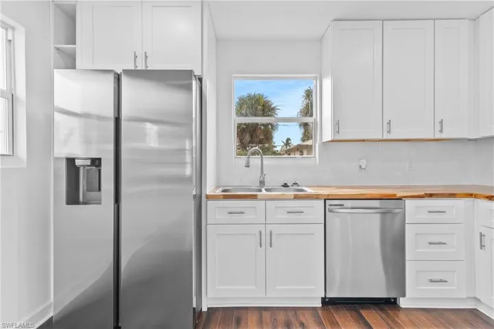 Kitchen featuring stainless steel appliances, white cabinets, dark wood-style floors, open shelves, and backsplash
