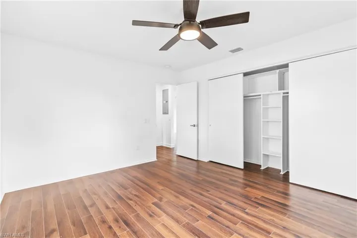 Unfurnished bedroom with a ceiling fan, a closet, and dark wood-type flooring