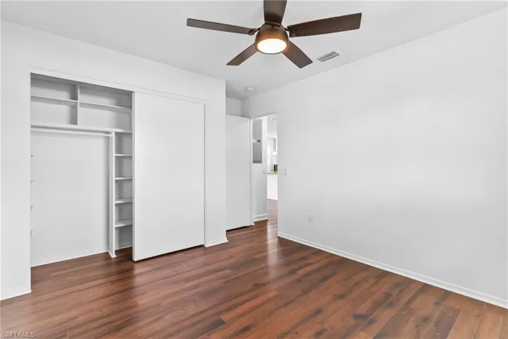 Unfurnished bedroom featuring dark wood-style floors, a closet, and ceiling fan
