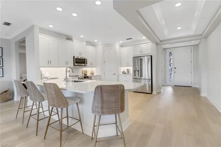 Kitchen with a kitchen breakfast bar, visible vents, a sink, crown molding, and appliances with stainless steel finishes