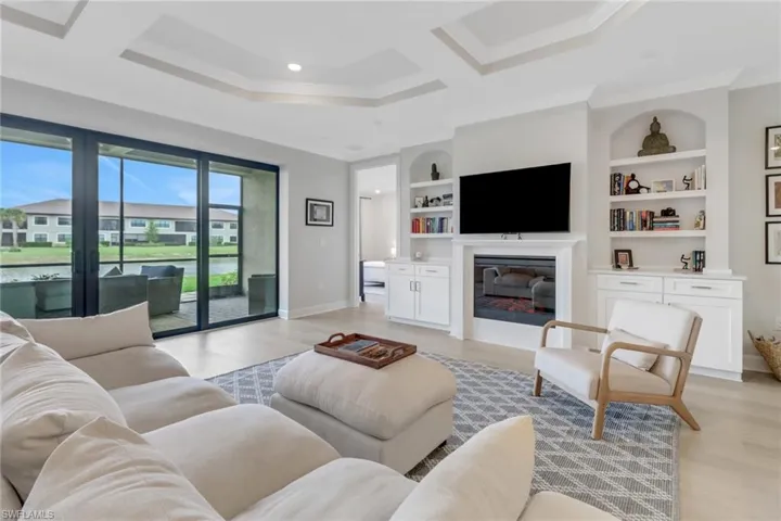 Living room with a glass covered fireplace, baseboards, light wood-style floors, and ornamental molding