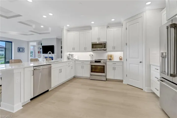 Kitchen with light wood finished floors, light countertops, a sink, appliances with stainless steel finishes, and white cabinetry