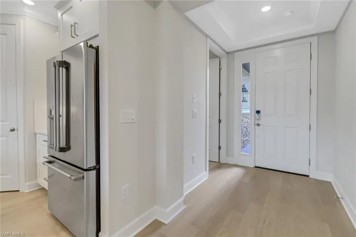 Foyer featuring light wood-type flooring, baseboards, recessed lighting, and a raised ceiling