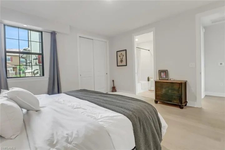 Bedroom featuring light wood-type flooring, ensuite bath, baseboards, and a closet