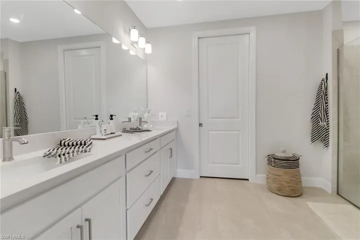 Full bath featuring a tile shower, tile patterned flooring, a sink, and double vanity