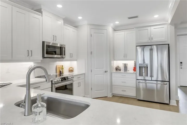 Kitchen featuring stainless steel appliances, backsplash, a sink, and white cabinetry
