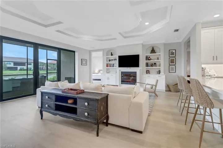 Living room with light wood-type flooring, built in features, visible vents, and crown molding