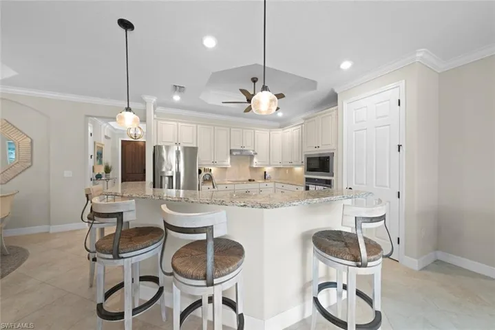 Kitchen featuring light-toned cabinetry, granite countertops, stainless steel appliances, and tile flooring