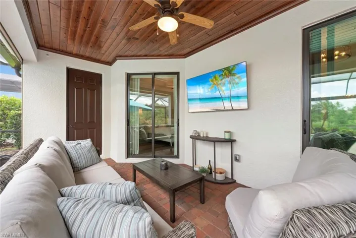 Screened patio featuring a wood-finish plank ceiling, ceiling fan with integrated lighting, and red brick flooring