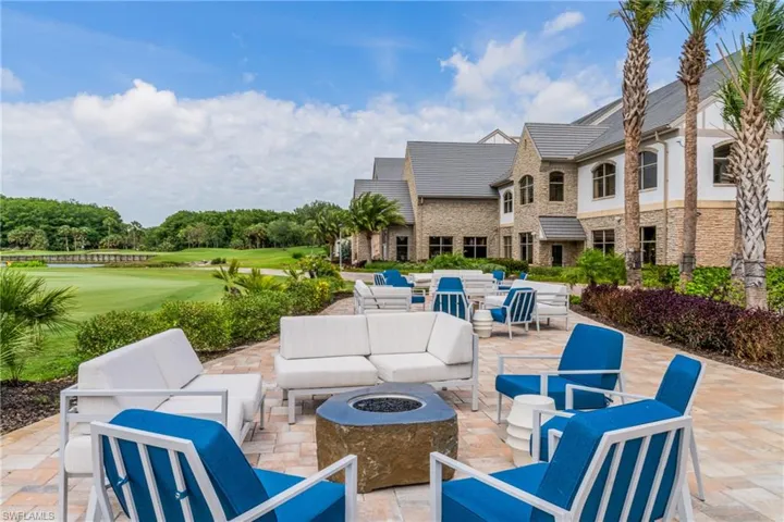 Expansive paver patio featuring a built-in fire pit, surrounded by lush landscaping and a manicured golf course