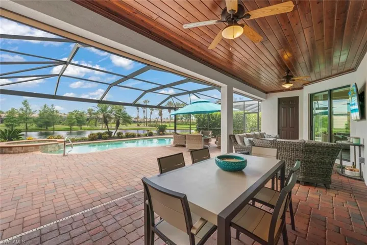 Expansive screened lanai featuring a swimming pool, integrated spa, and brick paver decking