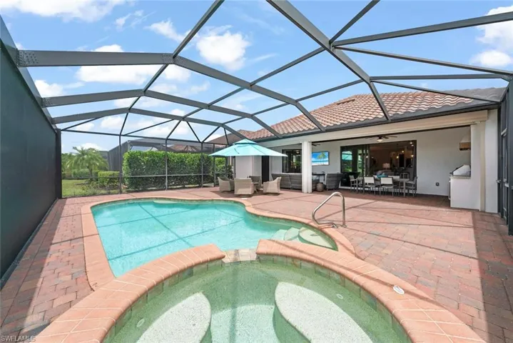 Screened lanai featuring a swimming pool and attached spa with brick coping