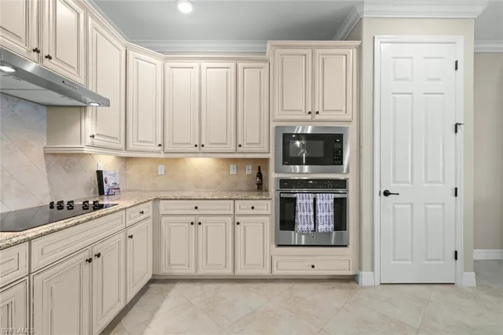 Kitchen featuring light-toned cabinetry with dark hardware, granite countertops, and a tiled backsplash