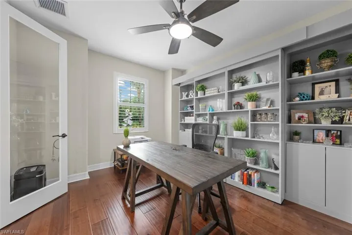 Spacious interior den or office featuring tile flooring, built-in murphy bed, window with plantation shutters.