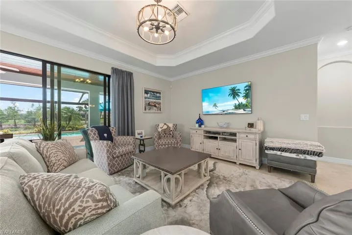 Living area featuring large sliding glass doors, a tray ceiling with crown molding, and a decorative ceiling light fixture