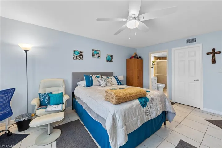 Bedroom with a ceiling fan, light tile patterned floors, and ensuite bathroom