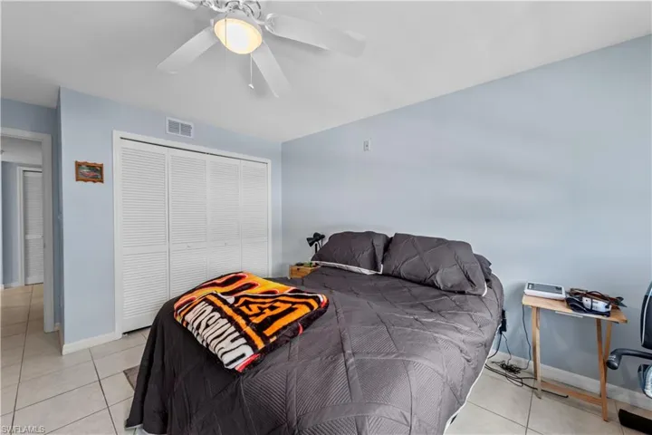 Bedroom with a closet, light tile patterned flooring, and ceiling fan