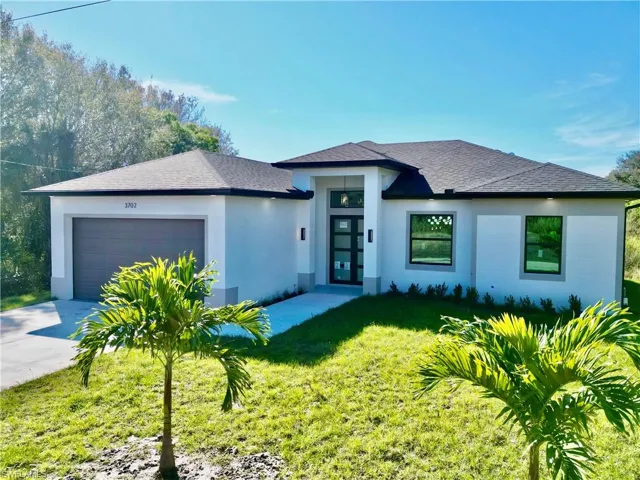 View of front of home featuring a front lawn, a garage, stucco siding, a shingled roof, and driveway