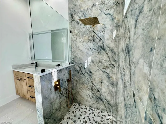 Bathroom with vanity, a marble finish shower, and light tile patterned floors