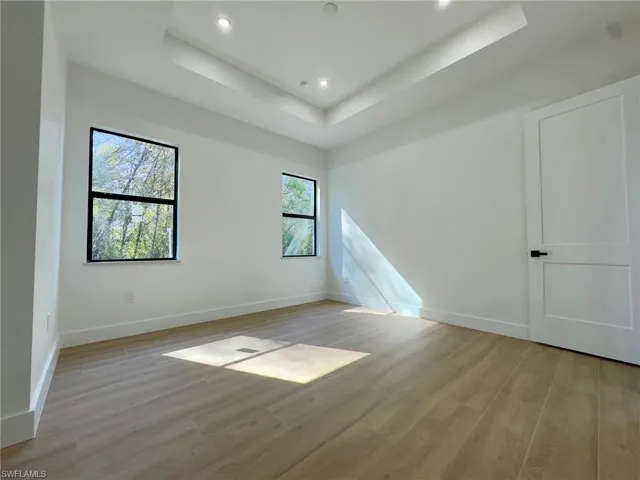 Unfurnished room featuring light wood-type flooring, recessed lighting, and a raised ceiling