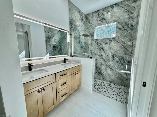 Bathroom with double vanity and a marble finish shower