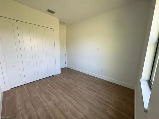 Unfurnished bedroom with dark wood-style flooring and a closet
